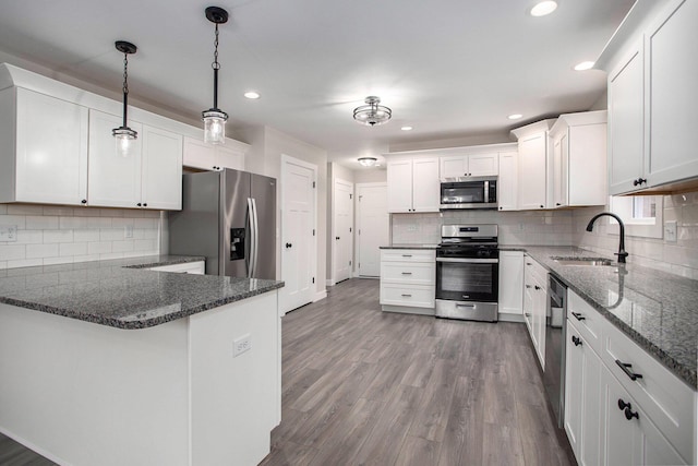 kitchen featuring white cabinetry, sink, stainless steel appliances, and hanging light fixtures