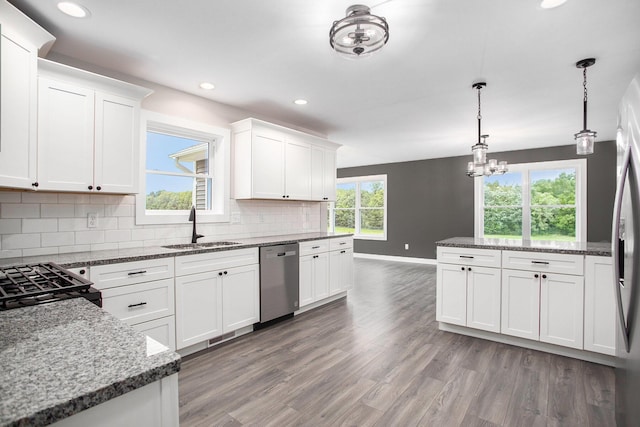 kitchen featuring sink, hardwood / wood-style flooring, stainless steel dishwasher, pendant lighting, and white cabinets