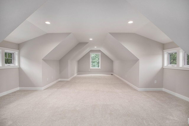 bonus room with light carpet, a wealth of natural light, and lofted ceiling