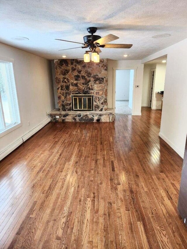 unfurnished living room featuring hardwood / wood-style floors, a textured ceiling, ceiling fan, and a fireplace