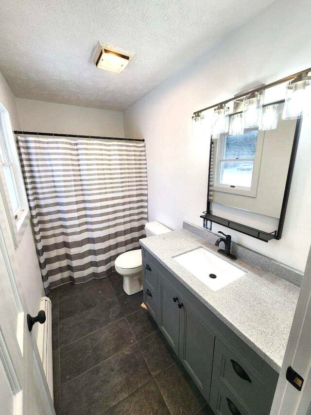 bathroom featuring toilet, a textured ceiling, vanity, and tile flooring