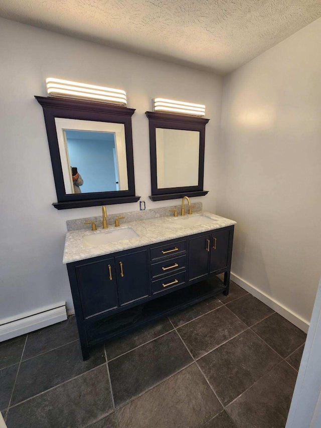 bathroom featuring dual bowl vanity, a baseboard heating unit, a textured ceiling, and tile floors