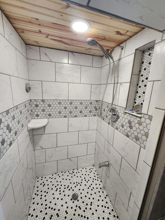 bathroom with a tile shower and wooden ceiling