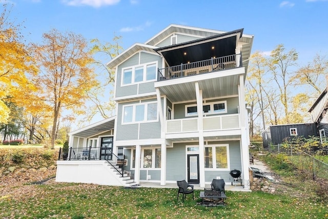 rear view of property with a lawn, a balcony, and an outdoor fire pit