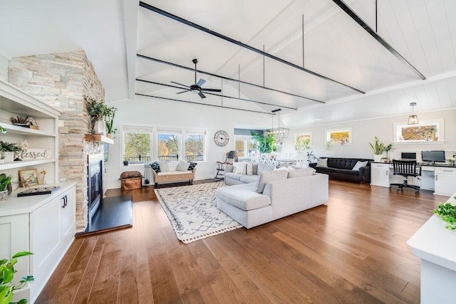 living room with a stone fireplace, dark hardwood / wood-style floors, high vaulted ceiling, ceiling fan, and beam ceiling