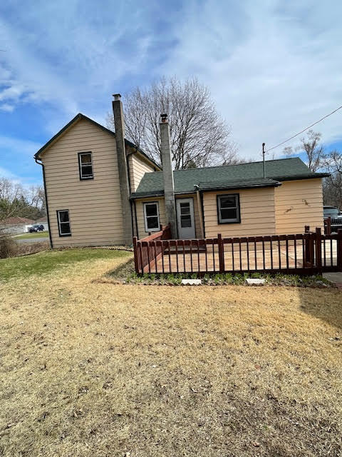 back of house featuring a wooden deck and a yard