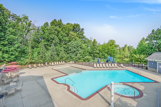 view of pool with a hot tub, a patio, and a playground