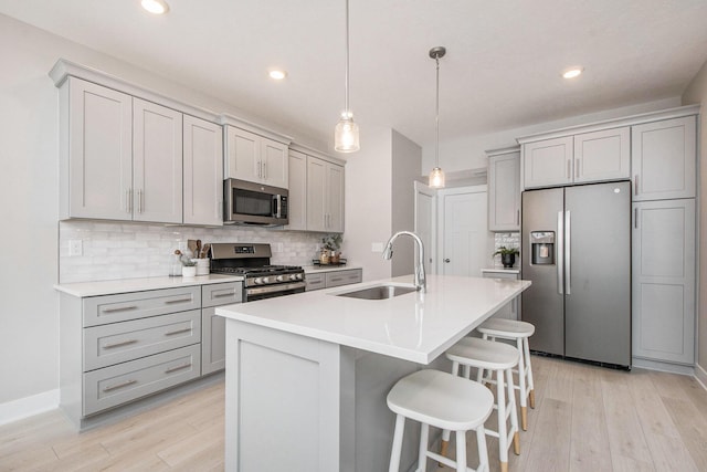 kitchen featuring sink, gray cabinetry, a center island with sink, appliances with stainless steel finishes, and pendant lighting