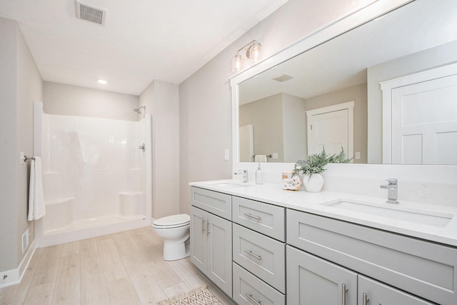 bathroom featuring vanity, wood-type flooring, toilet, and a shower