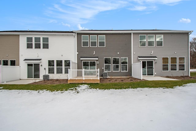 snow covered house featuring cooling unit and a patio area