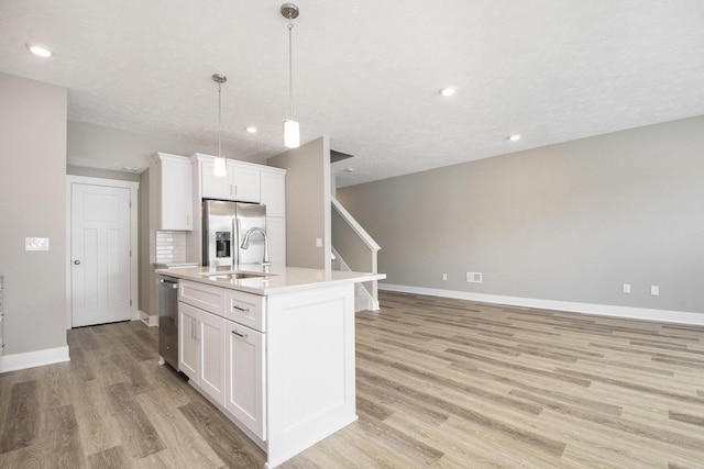 kitchen with appliances with stainless steel finishes, sink, a center island with sink, and white cabinets