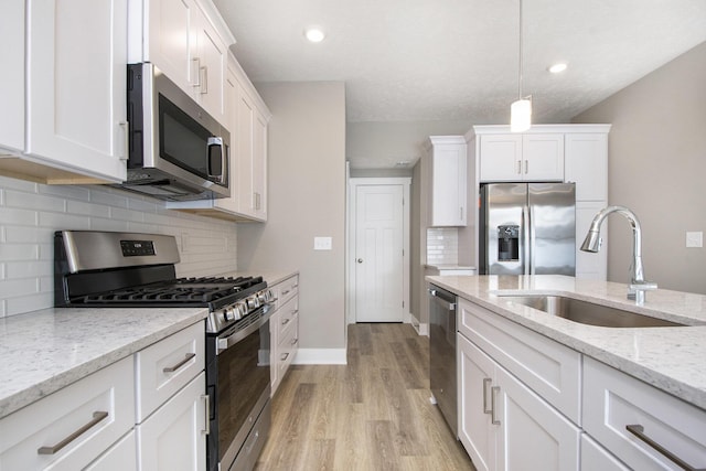 kitchen featuring pendant lighting, sink, appliances with stainless steel finishes, white cabinetry, and light stone counters