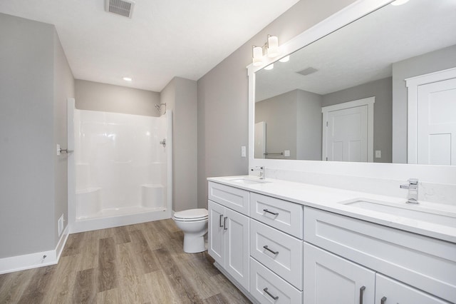 bathroom featuring vanity, wood-type flooring, toilet, and a shower