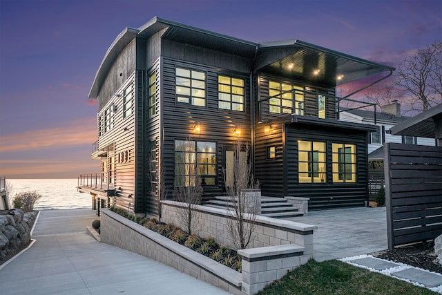 modern home featuring a balcony, a water view, and a patio