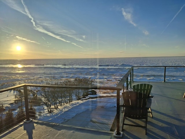 balcony at dusk featuring a water view