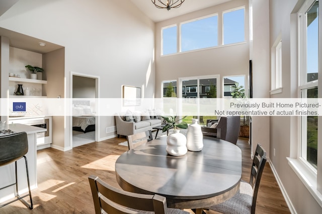 dining area featuring light wood-type flooring and high vaulted ceiling