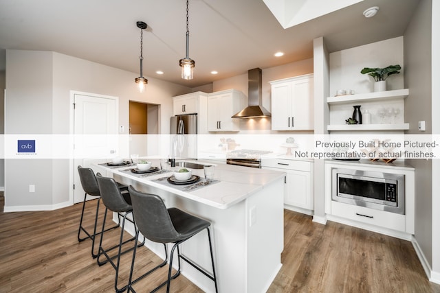 kitchen featuring stainless steel appliances, wall chimney range hood, dark hardwood / wood-style flooring, pendant lighting, and white cabinets