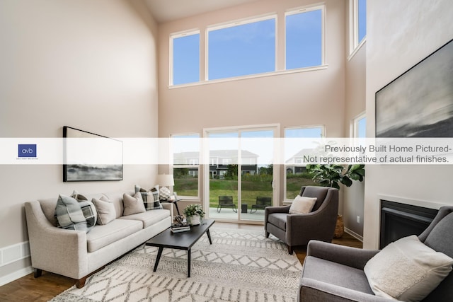 living room with hardwood / wood-style floors, plenty of natural light, and a high ceiling