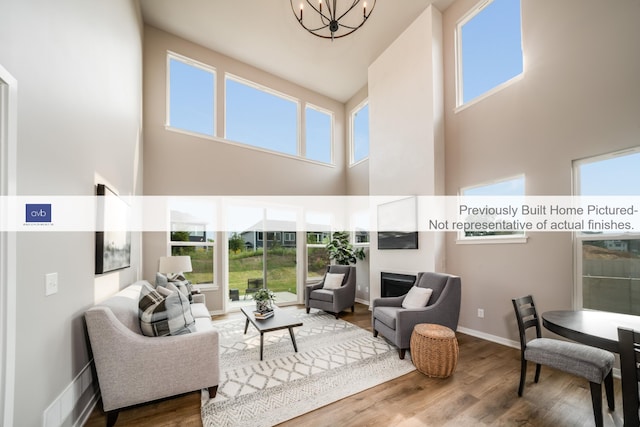 living room with an inviting chandelier, a high ceiling, and hardwood / wood-style flooring