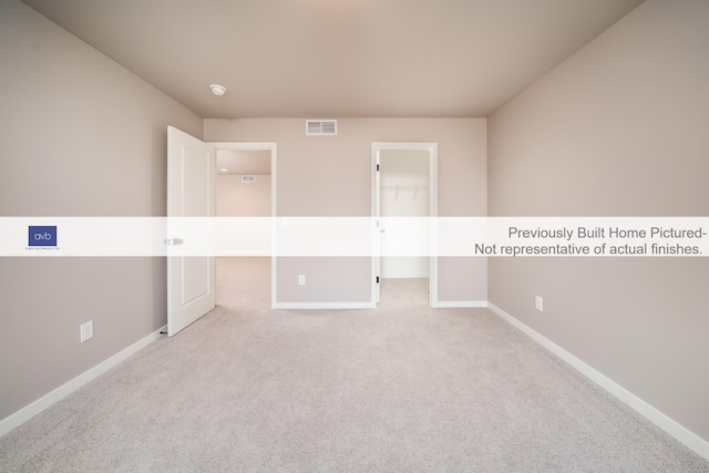 unfurnished bedroom with light colored carpet, a spacious closet, and a closet