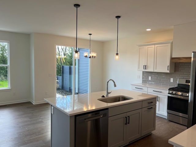 kitchen with sink, decorative backsplash, appliances with stainless steel finishes, an island with sink, and dark hardwood / wood-style flooring