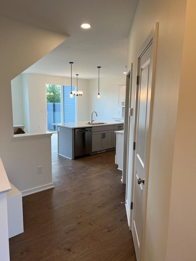 kitchen featuring dark hardwood / wood-style flooring, white cabinets, hanging light fixtures, an island with sink, and stainless steel dishwasher