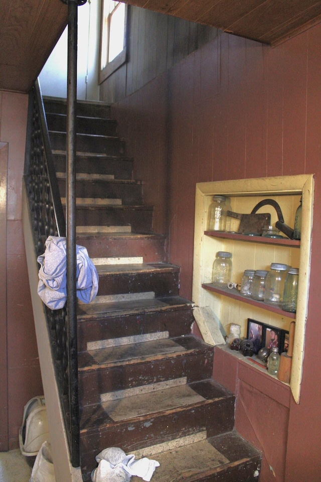 stairway featuring wooden walls