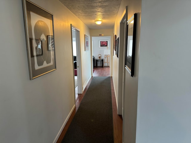 corridor with dark hardwood / wood-style floors and a textured ceiling