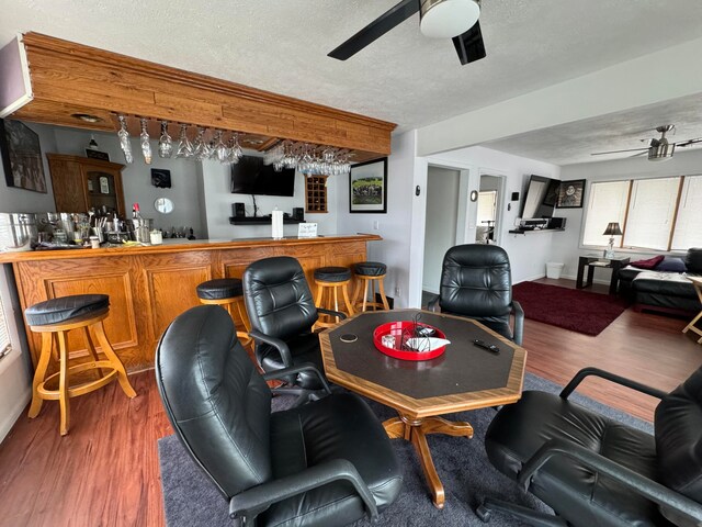 living room featuring dark hardwood / wood-style floors, ceiling fan, and indoor bar