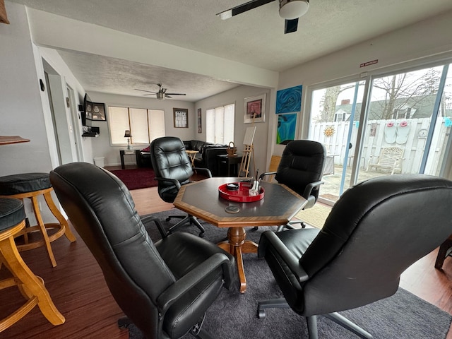 living room featuring hardwood / wood-style floors, ceiling fan, and a textured ceiling