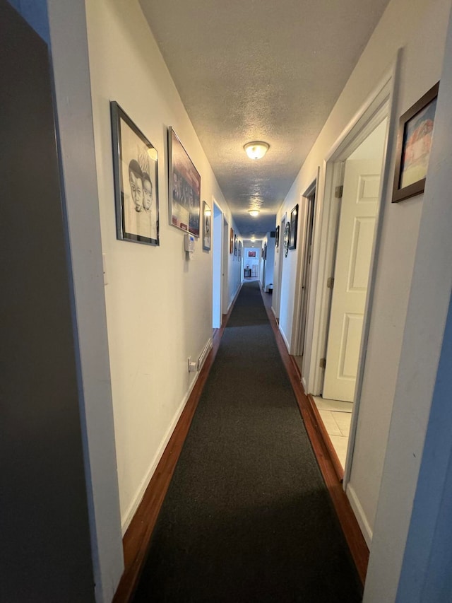 corridor featuring a textured ceiling and light colored carpet