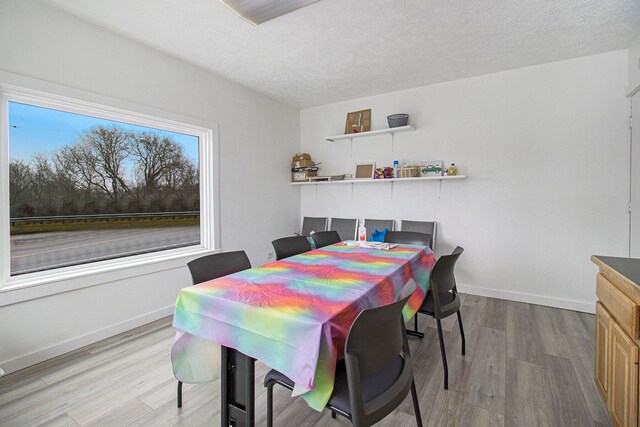 dining space featuring a textured ceiling and light wood-type flooring