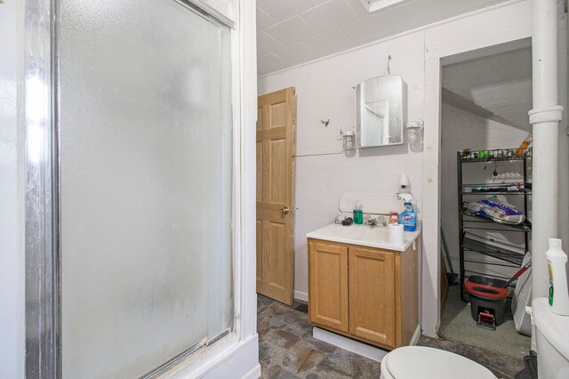 bathroom with a shower with door, toilet, and vanity