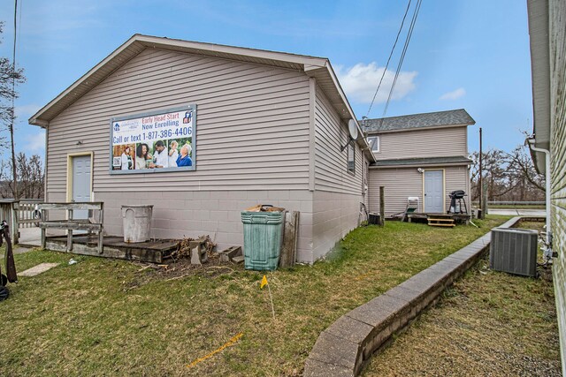 view of side of property featuring central AC and a yard