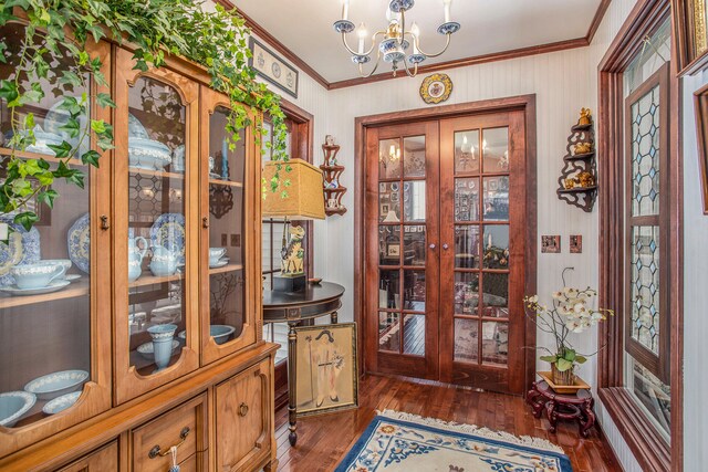 foyer featuring dark hardwood / wood-style flooring, an inviting chandelier, and crown molding