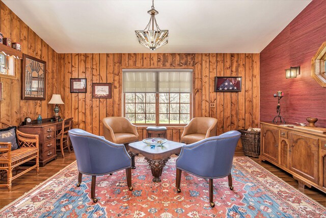 sitting room featuring vaulted ceiling, dark wood-type flooring, and wooden walls