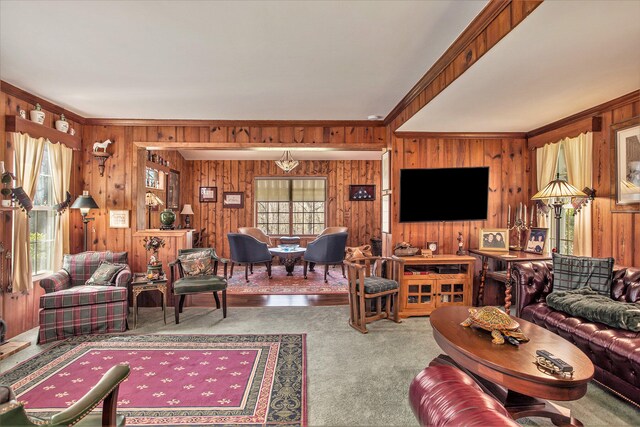 carpeted living room with wooden walls, ornamental molding, and a healthy amount of sunlight