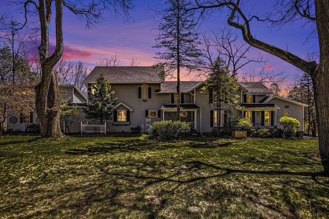 back house at dusk with a lawn