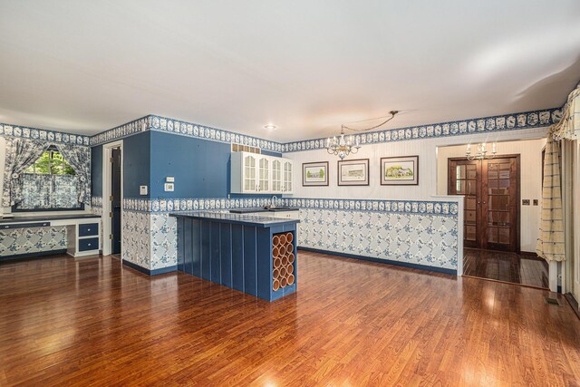 kitchen featuring pendant lighting, hardwood / wood-style flooring, kitchen peninsula, and an inviting chandelier