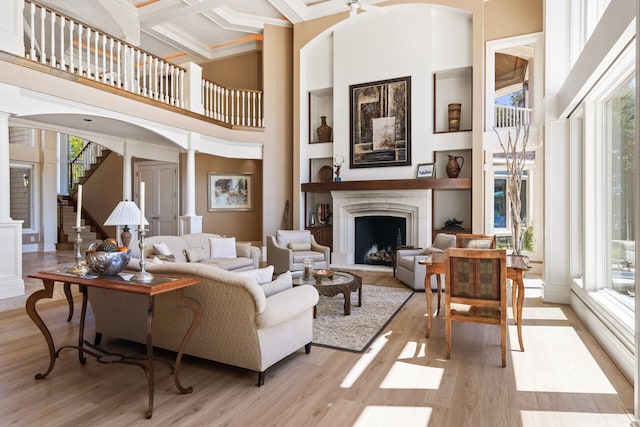 living room with coffered ceiling, plenty of natural light, decorative columns, and light hardwood / wood-style floors