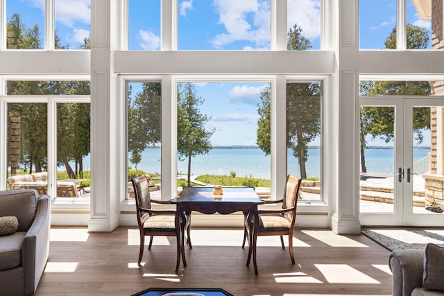 sunroom with a water view, french doors, and a wealth of natural light