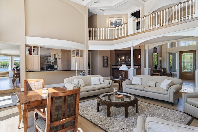 living room with ornate columns, coffered ceiling, a high ceiling, and beamed ceiling