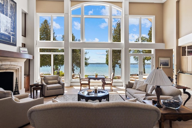 living room with a high ceiling, a water view, hardwood / wood-style flooring, and french doors