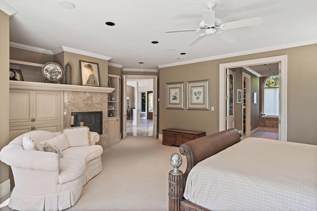 carpeted bedroom with a tile fireplace, ornamental molding, and ceiling fan