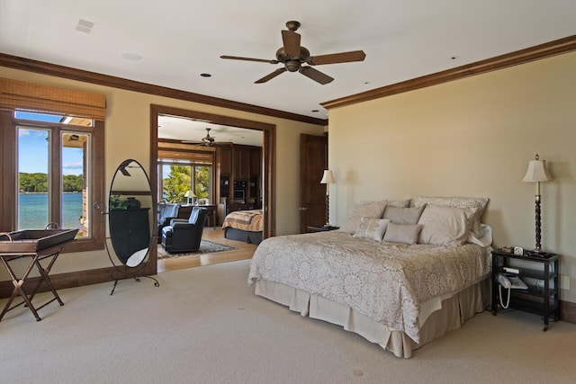 bedroom with ornamental molding, a water view, carpet, and ceiling fan