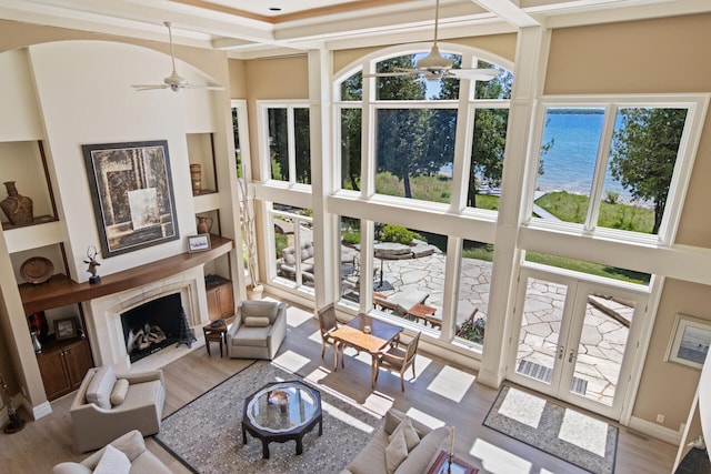 living room featuring a premium fireplace, a healthy amount of sunlight, ceiling fan, and french doors