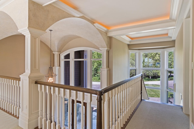 hall featuring ornate columns, carpet, and a chandelier