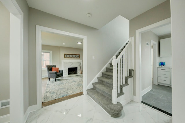 stairs with light tile floors and a high end fireplace