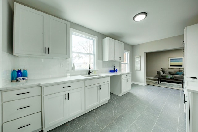 kitchen with tasteful backsplash, white cabinetry, sink, and tile flooring