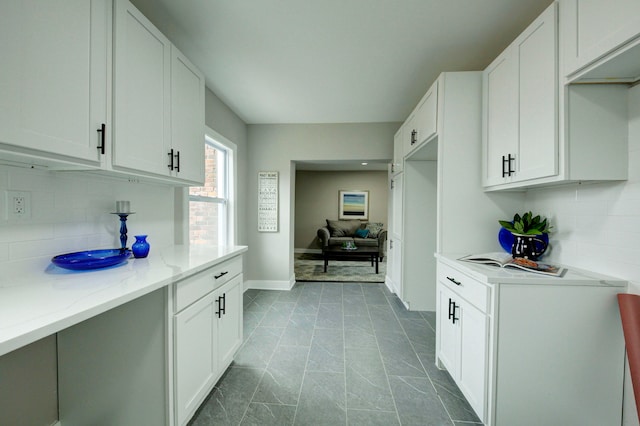 kitchen featuring backsplash, tile floors, white cabinets, and light stone counters